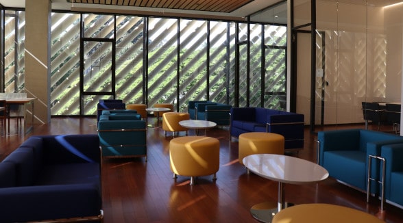 Sala de estudo com mesas, cadeiras e sofás.