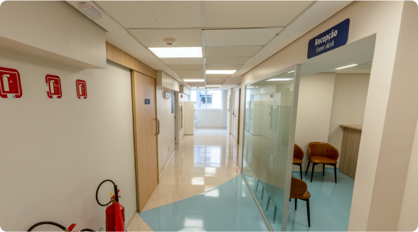 Espaço aberto no interior de um prédio com um banco longo de madeira para sentar.