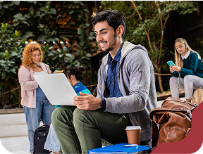 Estudantes universitários estudando e relaxando com laptops e celulares em área de convivência da Unidade de Ensino Einstein.