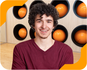 Estudante universitário sorrindo, usando camiseta vinho, no laboratório de Fisioterapia da Unidade de Ensino Einstein.