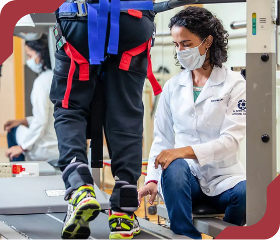 Fisioterapeuta do Einstein supervisionando paciente em reabilitação de marcha em esteira.